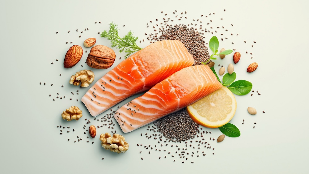 Filetti di salmone su un piatto con noci, mandorle, semi di chia, limone e foglie verdi su sfondo chiaro.